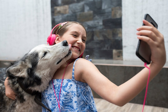 Girl taking selfie with dog through mobile phone at home