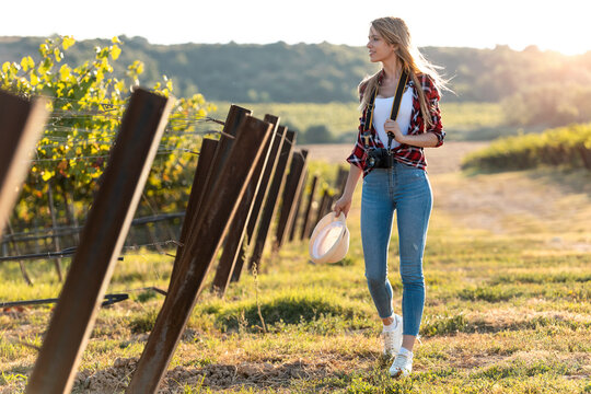 Young woman holding camera while walking at vineyard