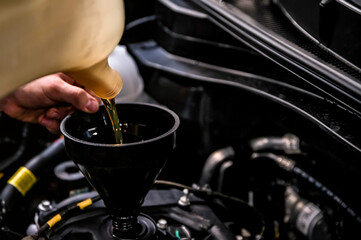 Close-up of mechanic adding oil with a funnel