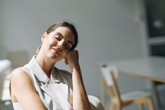 Woman with head in hands day dreaming while sitting on chair at office