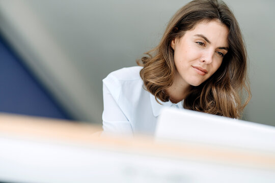 Businesswoman standing while working on laptop at office