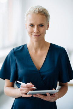 Close-up of smiling businesswoman using digital tablet while standing in office