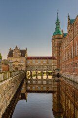 Fototapeta na wymiar Frederiksborg castle and bridge over the moat are reflected in the shiny water