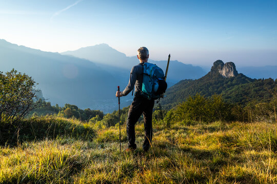 Male hiker with backpack looking at mountain against sky during sunrise, Orobie, Lecco, Italy