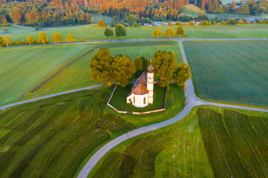 Germany, Bavaria, Etting, Drone view of Saint Andrew church surrounded by green fields at dawn