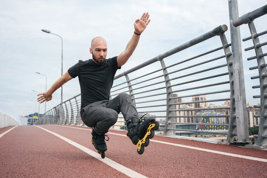Young man inline skating while crouching on bridge against sky