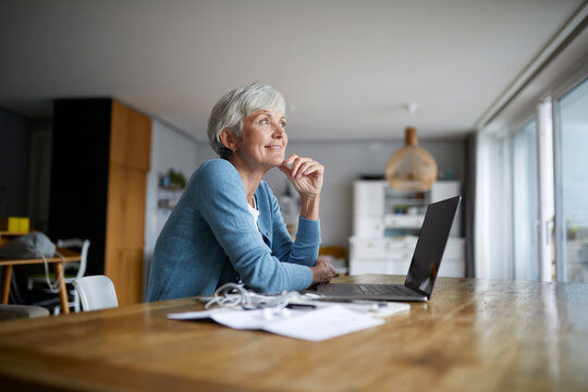 Contemplation senior woman with hand on chin sitting at home