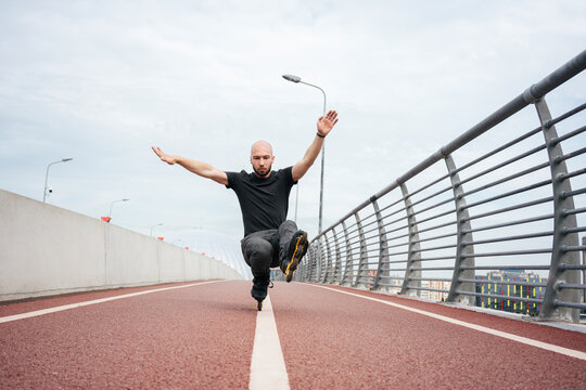 Young man performing stunt while inline skating on bridge against sky