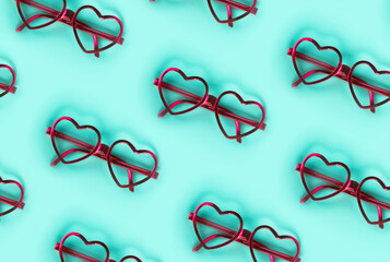 Directly above shot of pink heart shaped eyeglasses on blue background