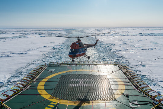 Helicopter landing on helipad of ice-breaker 50 Years of Victory cleaving through ice of Arctic Ocean