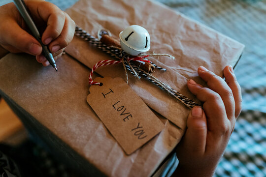 Hands of boy writing on Christmas present at home