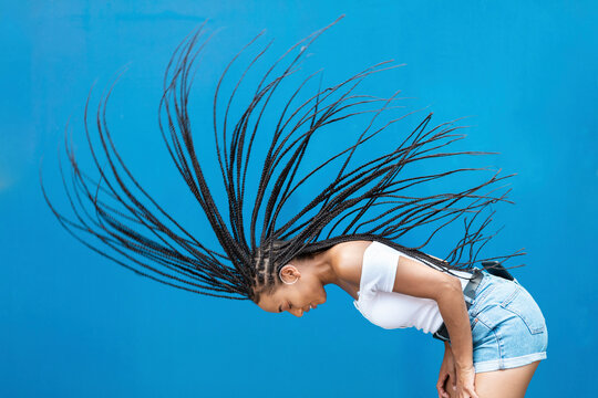 Woman tossing hair against blue wall