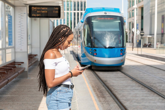 Young woman using phone while standing at tramway