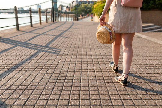 Legs of woman walking on pavement along riverside