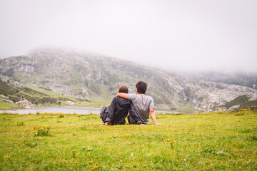 Fototapeta na wymiar Romatinc picture of a young couple in the mountains lying in the grass in a foggy day. Travel and explore freedom