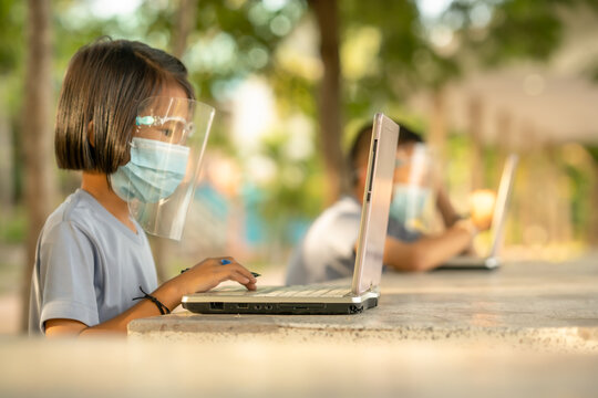 School Child Sitting Outdoor Of Classroom, Kid Looking And Learning On Notebook Computer, They Wearing Mask And Social Distance For Safety Coronavirus