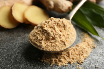 Dry ginger powder in spoon on grey table, closeup