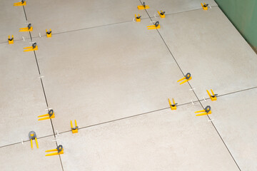 A tile leveling system. Floor tiling with using leveling clips (wedges) and tile spacers