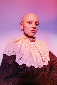 Young hairless model in vintage earrings and jabot