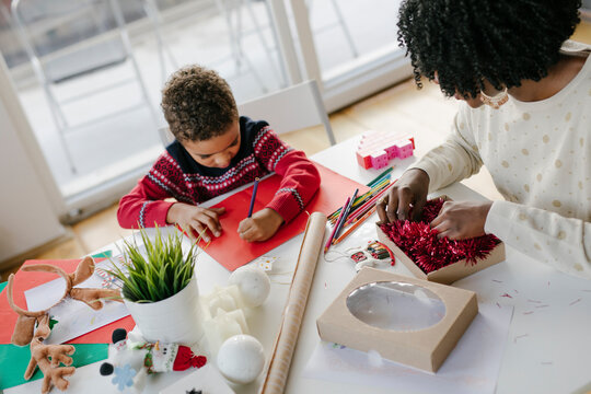 Little boy making christmas card with his mother