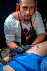 Master tattooist demonstrates the process of getting tattoo in tattoo parlor