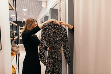 Shop assistant helping customer in fitting room