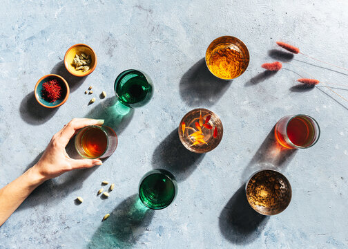 hand holding chai tea in drinking glass with spices, light and shadow