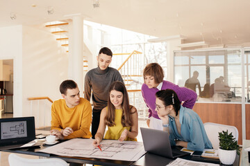 Young colleagues examining blueprint together