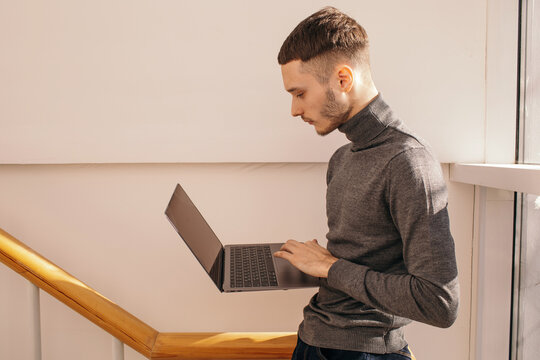 Young man using laptop near window