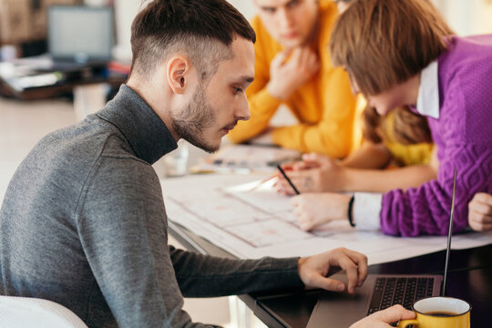 Man using laptop near colleagues
