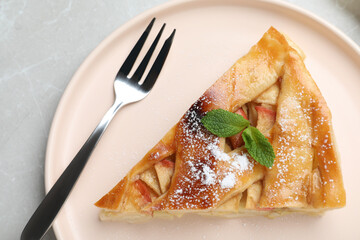 Slice of traditional apple pie on light marble table, top view
