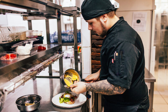 Focused male chef serving dish in kitchen