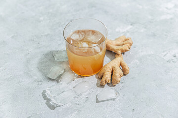 Ginger drink in glass with ginger and ice cubes
