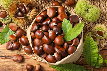Fresh sweet edible chestnuts on wooden table, flat lay