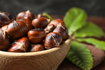 Delicious roasted edible chestnuts in wooden bowl, closeup