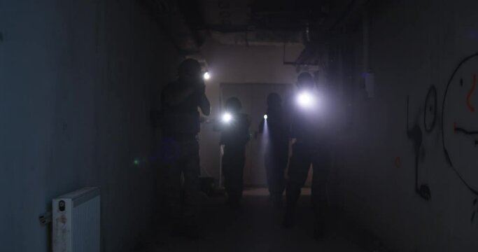 Soldiers with flashlights inspecting dark corridor
