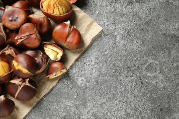 Delicious roasted edible chestnuts on grey table, flat lay. Space for text