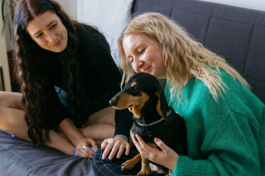 Two young women spending time together indoor with their small d