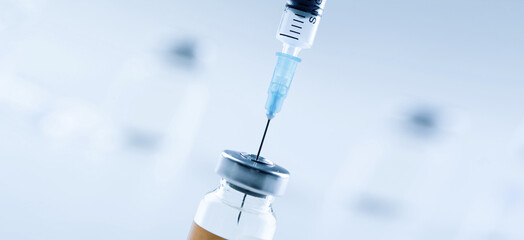 Medical syringe with a needle and a bollte with vaccine.