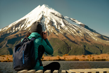 Fototapeta na wymiar Young woman taking a photo at Mount Taranaki in Egmont National Park, New Zealand