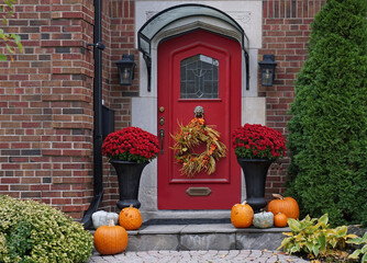 Front door of house decorated with fall wreath and pumpkins