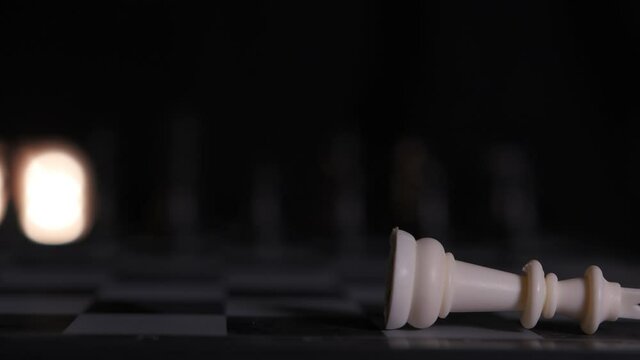 Close-up of a chessboard as a player knocks over the king, winning the game.