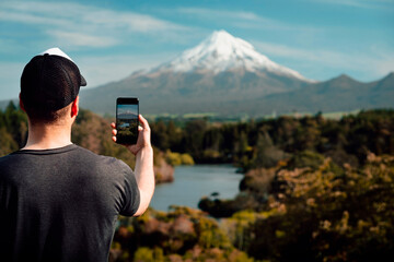 Man taking picture with mobile at Mount Taranaki, New Zealand.