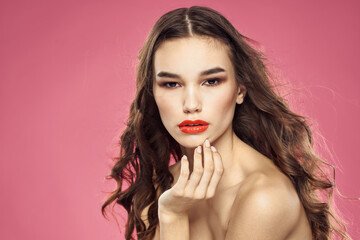 Fototapeta premium Beautiful woman with red lips on a pink background nude shoulders cropped view