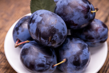 heap of a purple damsons plums over grunge wooden background. natural fruits. healthy eating concept