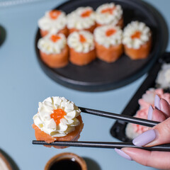 Sushi set on blue background. Closeup of sushi rolls with chopsticks