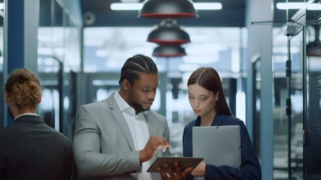 Multiracial couple speaking in office. Businessman showing meeting topic to girl