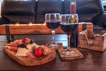 Red wine with Charcuterie board on rustic wood with candles behind a spread of prosciutto panino
