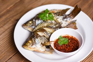 Tilapia freshwater fish on white plate with chili sauce - cooked food grilled tilapia fish