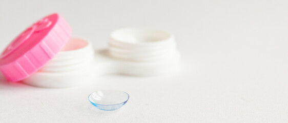 Contact lens, case and tweezers on gray background. Selective focus. Close up